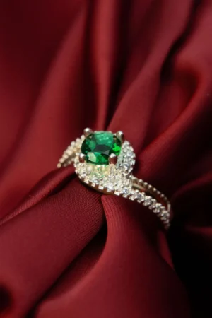 "Anillo en plata ley 925 con esmeralda de corte oval y circones, diseño único, fotografiado sobre tela roja